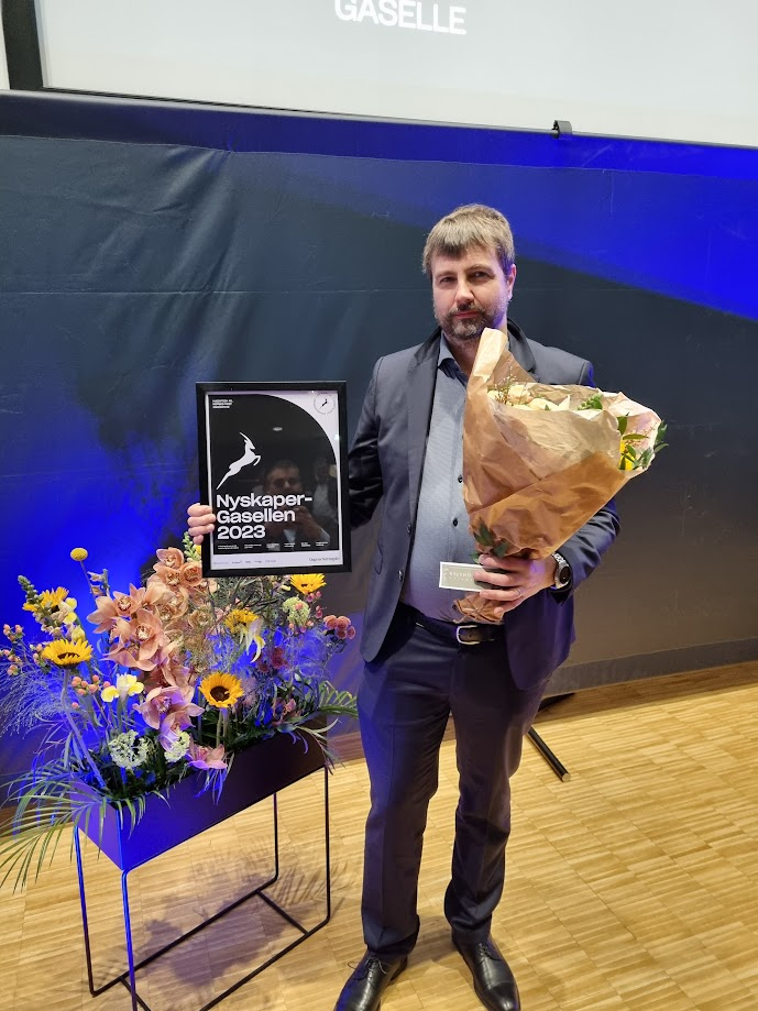 Kjetil Helland with flowers and the award on stage
